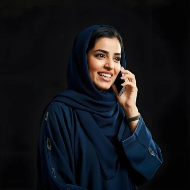 Communicating and checking on friends, a close-up portrait of a veiled Saudi Arabian Gulf woman making a voice call via mobile phone, answering and replying to calls using the mobile phone, expressions of joy upon hearing good news, spending enjoyable times exchanging news and conversations, black background