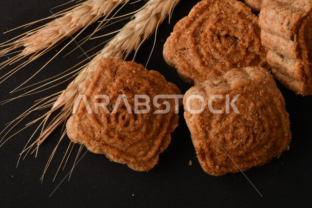 صورة مقربة لمعمول محشو مربع الشكل من الحلويات الشعبية الهشة اللذيذة على خلفية سوداء ، صورة لكعك بعجوة وبعرف بإسم كعك العيد الشهي ، خلفية سوداء لحلويات شعبية طازجة