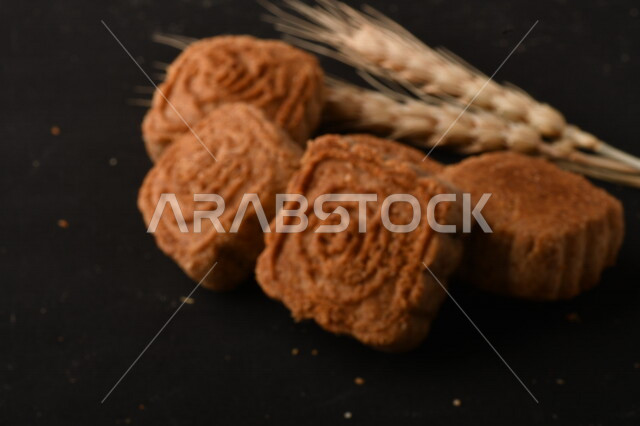 صورة مقربة لمعمول محشو مربع الشكل من الحلويات الشعبية الهشة اللذيذة على خلفية سوداء ، صورة لكعك بعجوة وبعرف بإسم كعك العيد الشهي ، خلفية سوداء لحلويات شعبية طازجة