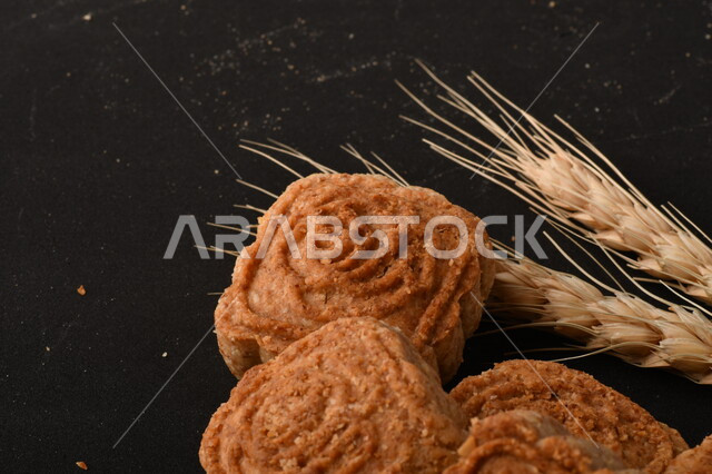 صورة مقربة لمعمول محشو مربع الشكل من الحلويات الشعبية الهشة اللذيذة على خلفية سوداء ، صورة لكعك بعجوة وبعرف بإسم كعك العيد الشهي ، خلفية سوداء لحلويات شعبية طازجة