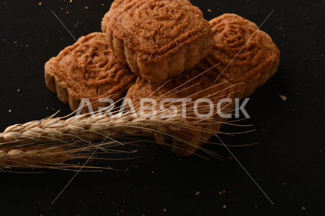 صورة مقربة لمعمول محشو مربع الشكل من الحلويات الشعبية الهشة اللذيذة على خلفية سوداء ، صورة لكعك بعجوة وبعرف بإسم كعك العيد الشهي ، خلفية سوداء لحلويات شعبية طازجة