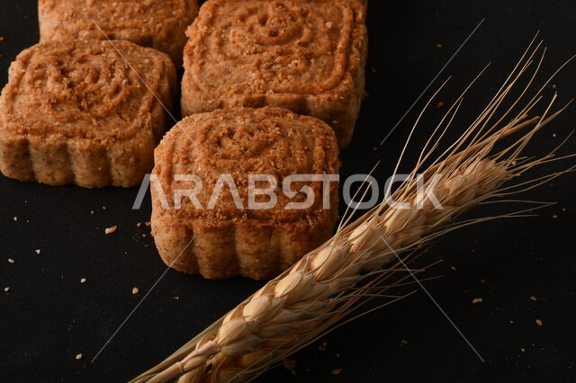 صورة مقربة لمعمول محشو مربع الشكل من الحلويات الشعبية الهشة اللذيذة على خلفية سوداء ، صورة لكعك بعجوة وبعرف بإسم كعك العيد الشهي ، خلفية سوداء لحلويات شعبية طازجة