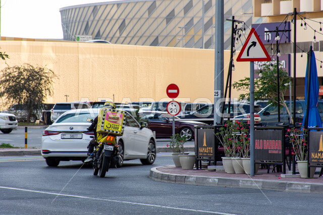عمليات شحن الطلبات الموثوقة و الآمنة في الإمارات العربية المتحدة, صورة من الخلف لمندوب عربي خليجي إماراتي يقود دراجة نارية لتوصيل الطعام من شركة نون, خدمات التوصيل السريع في مدينة دبي