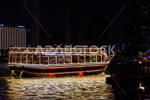 Reflection of lights on sea water, tourist attractions from around the world, illuminated wooden boat for transporting tourists illuminated in Dubai, fun sea tours at night, coastal tourist places in the United Arab Emirates