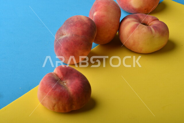 صورة لفاكهة الخوخ اللذيذ على خلفية ملونة باللونين الأصفر والأزرق ، فاكهة الدّراق الصحية اللذيذة ، فاكهة صيفية