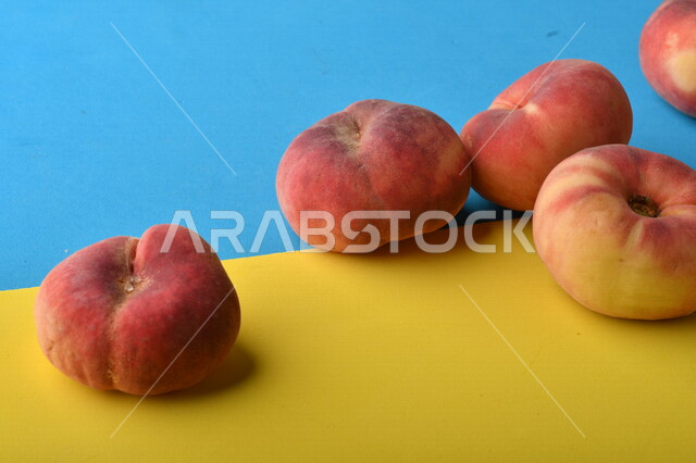 صورة لفاكهة الخوخ اللذيذ على خلفية ملونة باللونين الأصفر والأزرق ، فاكهة الدّراق الصحية اللذيذة ، فاكهة صيفية