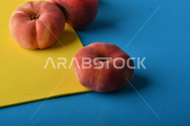 صورة لفاكهة الخوخ اللذيذ على خلفية ملونة باللونين الأصفر والأزرق ، فاكهة الدّراق الصحية اللذيذة ، فاكهة صيفية