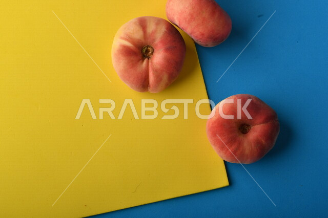 صورة لفاكهة الخوخ اللذيذ على خلفية ملونة باللونين الأصفر والأزرق ، فاكهة الدّراق الصحية اللذيذة ، فاكهة صيفية