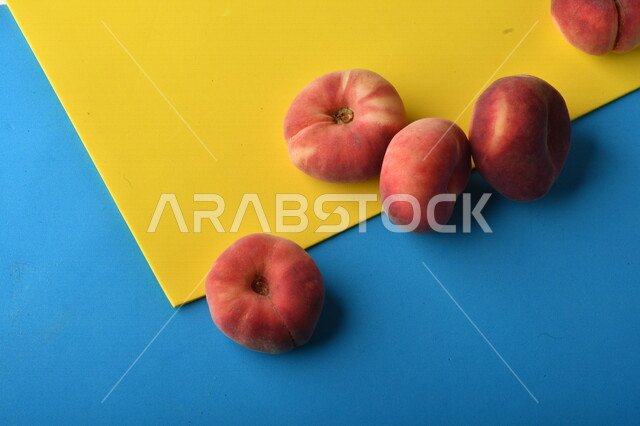 صورة لفاكهة الخوخ اللذيذ على خلفية ملونة باللونين الأصفر والأزرق ، فاكهة الدّراق الصحية اللذيذة ، فاكهة صيفية