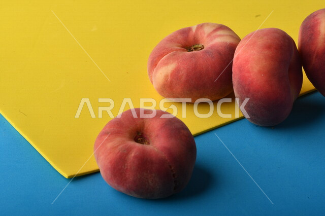 صورة لفاكهة الخوخ اللذيذ على خلفية ملونة باللونين الأصفر والأزرق ، فاكهة الدّراق الصحية اللذيذة ، فاكهة صيفية