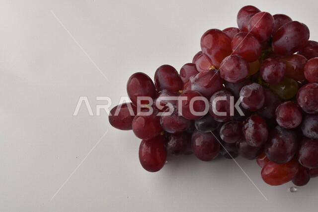 فاكهة العنب الأرجواني اللذيذ على خلفية بيضاء ، فاكهة العنب الصحية اللذيذة تظهر على شكل عناقيد ، فاكهة صيفية