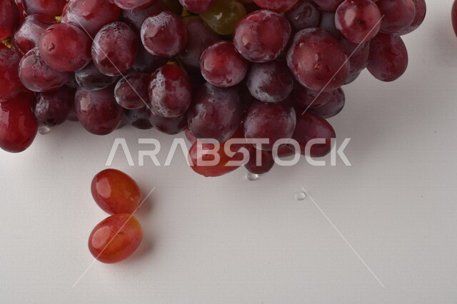 فاكهة العنب الأرجواني اللذيذ على خلفية بيضاء ، فاكهة العنب الصحية اللذيذة تظهر على شكل عناقيد ، فاكهة صيفية