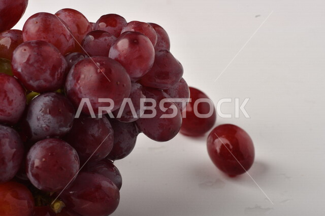 فاكهة العنب الأرجواني اللذيذ على خلفية بيضاء ، فاكهة العنب الصحية اللذيذة تظهر على شكل عناقيد ، فاكهة صيفية