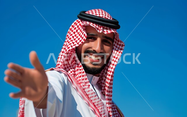 إيماءات السعادة والتحية والسلام والترحيب، بورتريه مقرب لرجل عربي خليجي سعودي يرتدي الشماغ السعودي والثوب الابيض يمد يده بإشارة المصافحة، خلفية زرقاء