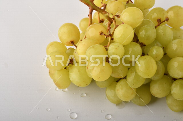 فاكهة العنب الأخضر اللذيذ على خلفية بيضاء ، صورة مقربة لفاكهة العنب الصحية اللذيذة تظهر على شكل عناقيد ، فاكهة صيفية