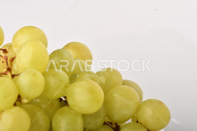 فاكهة العنب الأخضر اللذيذ على خلفية بيضاء ، صورة مقربة لفاكهة العنب الصحية اللذيذة تظهر على شكل عناقيد ، فاكهة صيفية
