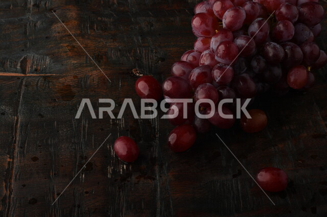 صورة لفاكهة العنب الأرجواني اللذيذ مصورة على طاولة خشبية ، فاكهة العنب الصحية اللذيذة تظهر على شكل عناقيد ، فاكهة صيفية