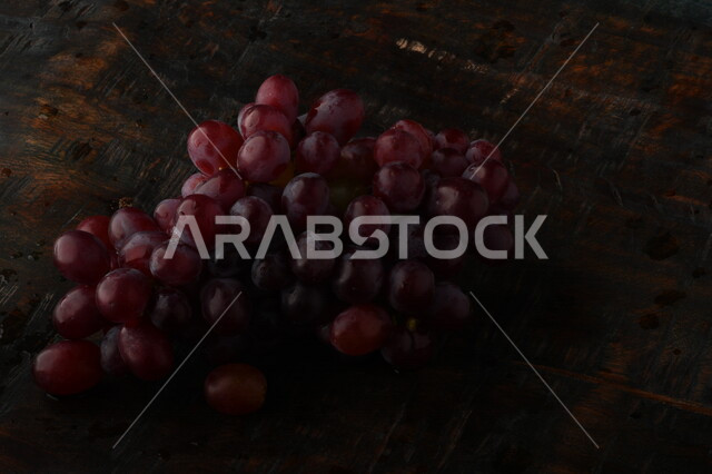 صورة لفاكهة العنب الأرجواني اللذيذ مصورة على طاولة خشبية ، فاكهة العنب الصحية اللذيذة تظهر على شكل عناقيد ، فاكهة صيفية