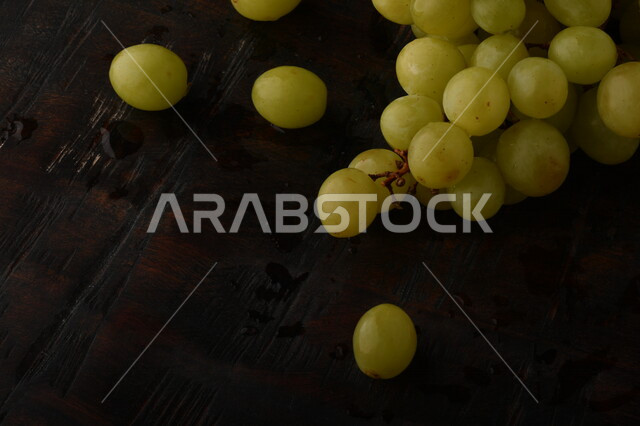 صورة لفاكهة العنب الأخضر اللذيذ على طاولة خشبية ، فاكهة العنب الصحية اللذيذة تظهر على شكل عناقيد ، فاكهة صيفية