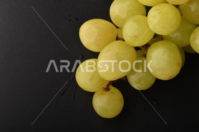 صورة لفاكهة العنب الأخضر اللذيذ على طاولة خشبية ، فاكهة العنب الصحية اللذيذة تظهر على شكل عناقيد ، فاكهة صيفية
