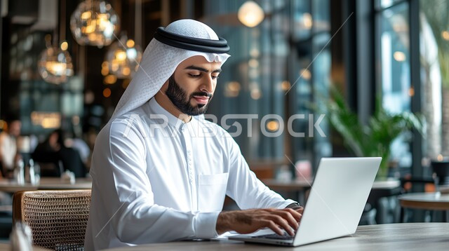 إنجاز المهام المطلوبة، مهن ووظائف مكتبية سعودية، إدارة شؤون الشركة وتنظيمها عبر الاجهزة التقنية، دمج العمل مع التكنولوجيا، رجل أعمال عربي خليجي سعودي يرتدي الزي التقليدي والغترة يعمل على الحاسوب المحمول, العمل في المجال الاقتصادي
