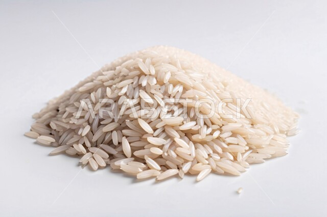 محصول الارز الزراعي, ارز ابيض غير مطبوخ, أرز ابيض منثور على الأرض, محاصيل زراعيه ، صورة بورتريه بخلفية بيضاء مليئ بحبيبات الارز