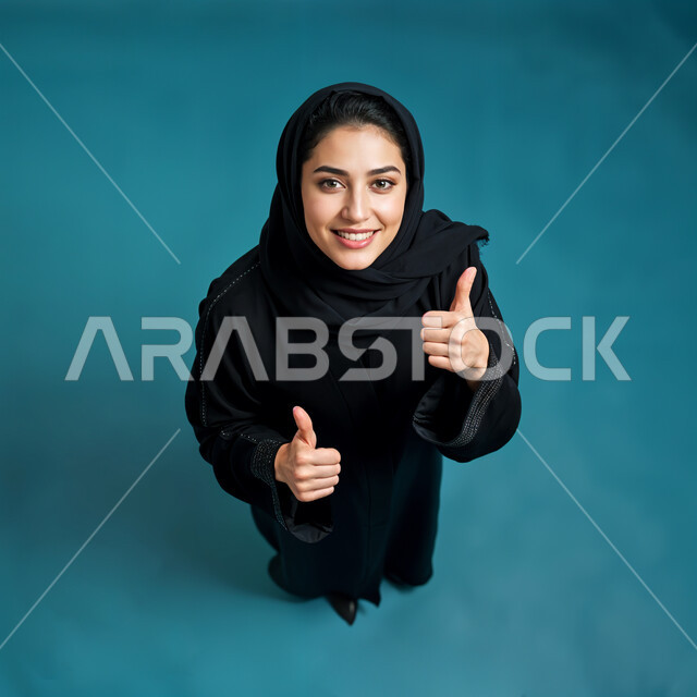 إيماءات الابتسامه السرور والثقه بالنفس ، الذكاء الاصطناعي مفهوم النعومة و الأنوثة، الاهتمام بالأناقة والمظهر الخارجي، صورة مقربة لامرأة عربيه خليجيه سعودية مبتسمة محجبة ترتدي العباءة والحجاب،  أزياء محجبات عصرية حديثة, خلفية زرقاء