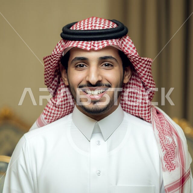 The concept of elegance and masculinity, a close-up of a smiling young Saudi Arabian Gulf man wearing a traditional shemagh and thobe looking at the camera with gestures of happiness and pleasure, taking care of one's outward appearance