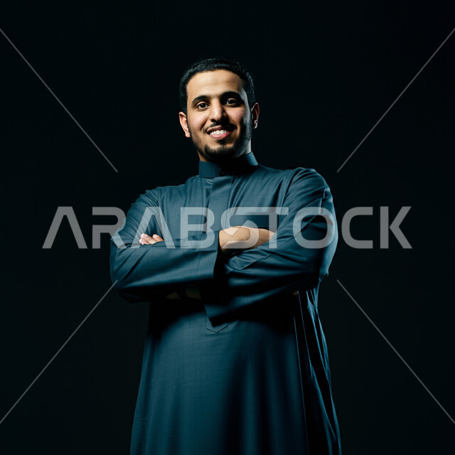 The concept of prestige and masculinity, elegance and interest in external appearance, close-up portrait of a Saudi Arabian Gulf man wearing traditional folk costume looking at the camera with expressions of pleasure and self-confidence, black background