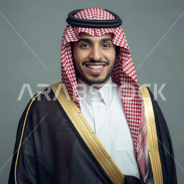 The concept of handsomeness and masculinity, taking selfies for official documents, elegance and interest in appearance, close-up portrait of a smiling Saudi Arabian Gulf man wearing a traditional shemagh and thobe looking at the camera with expressions of pleasure and self-confidence, gray background
