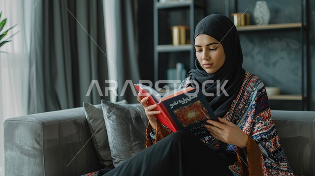ايماءات التركيز والاستمتاع، قراءة الروايات والقصص، تمضية وقت الفراغ بالتعلم والتثقيف الذاتي، قضاء أوقات هادئة في المنزل، امرأة عربية خليجية سعويةمحجبة تحمل بيدها كتاب، ممارسة هواية المطالعة