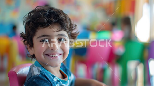 دور المدارس في رفع مستوى الوعي لدى الطلاب، صورة مقربة لطالب عربي خليجي سعودي يرتدي الزي المدرسي يجلس أمام الطاولة الدراسية بإيماءات وجه تدل على السعادة والسرور، المقررات والمناهج التعليمية الحديثة والمطورة بالسعودية، مفهوم العودة إلى المدارس
