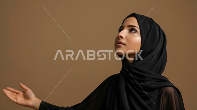 الحمد والشكر والتضرع و طلب العون، العباده والتقرب الى الله، بورتريه مقرب من الجانب لإمرأة مسلمة عربية خليجية سعودية ترتدي العباءة السوداء والحجاب ترفع يديها للدعاء، خلفية بيج