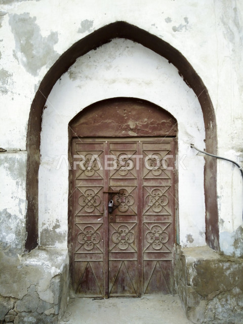 باب آثري قديم في السعودية بأسلوب تاريخي اسلامي ، معالم سياحة في المملكة العربية السعودية ، صورة خلفية لباب حجري قديم بارز الشكل ، باب قديم ، قفل نحاسي