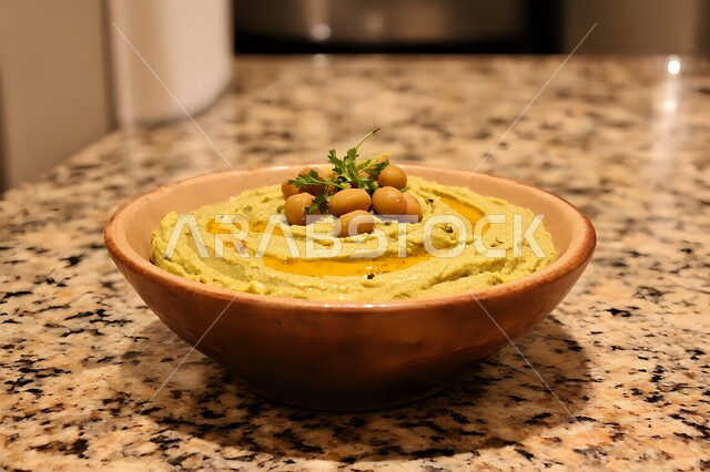 المقبلات النباتية الباردة اللذيذة، صورة مقربة لطبق من الحمص الكريمي اللذيذ المزين بزيت الزيتون والفلفل الحلو والحمص ، مأكولات وأطباق شعبية تقليدية، وصفات طعام شرقية عربية سعودية، فطور عربي تقليدي