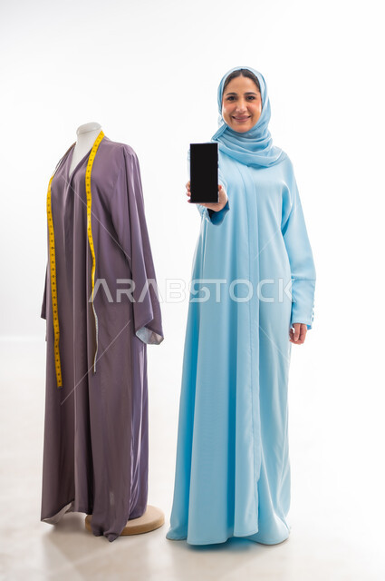 استخدام التقنيات الحديثة والأجهزة المتطورة في مجال الخياطة، اختراع وابتكار موديلات جديدة وعصرية، بورتريه لمصممة عمانية تقوم بعرض شاشة سوداء فارغة، ورشة عمل تصميم ازياء، مهن وأعمال فنية نسائية، فنون ومهارات تفصيل الملابس النسائية، مفهوم عالم الأزياء والموضة