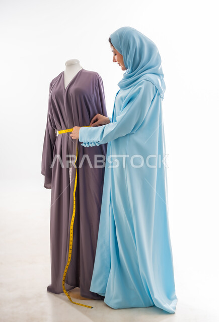 Using a tape measure to take the correct measurements, inventing and creating new and modern models, a portrait of an Omani designer taking measurements, a fashion design workshop, women's professions and artistic works, arts and skills of tailoring women's clothing, the concept of the world of fashion and style