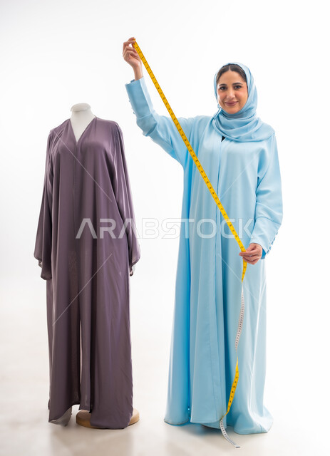 Arts and skills of women's clothing tailoring, invention and innovation of new and modern designs, portrait of an Omani designer holding a yellow tape measure in her hand, importance of women in the field of sewing, fashion design workshop, women's professions and artistic works, concept of the world of fashion and style