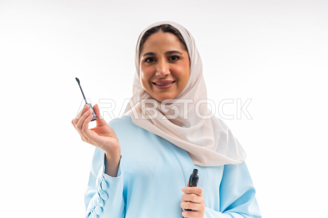 The concept of femininity and interest in beauty, skin and appearance, a Saudi expert in women's cosmetics, a close-up portrait of an Arab Gulf Omani woman wearing an abaya and hijab, marketing for makeup products, white background