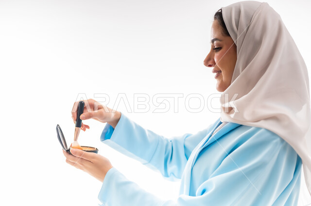مفهوم الأنوثة والاهتمام بالجمال والبشرة والمظهر الخارجي, خبيرة سعودية لمستحضرات التجميل النسائية، بورتريه مقرب لإمرأة عربية خليجية عمانية ترتدي العباءة والحجاب، التسويق لمنتجات الميك اب، خلفية بيضاء