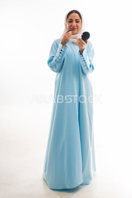 مفهوم الأنوثة والاهتمام بالجمال والبشرة والمظهر الخارجي, خبيرة لمستحضرات التجميل النسائية، بورتريه مقرب لإمرأة عربية خليجية عمانية ترتدي العباءة والحجاب، التسويق لمنتجات الميك اب، خلفية بيضاء