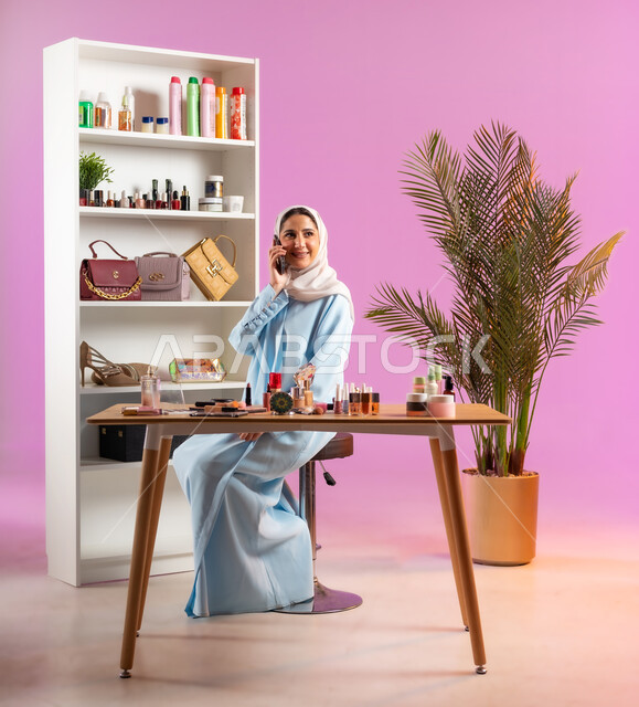 الدردشة مع الأهل والأصدقاء، إمرأة عربية خليجية عمانية ترتدي عباءة زرقاء تقوم بإجراء مكالمة هاتفية عبر الجوال، مفهوم الانوثه والاهتمام بالمظهر الخارجي, أدوات تجميل نسائيه عصريه، التسويق لمنتجات التجميل, مكياج وميكاب تتوريال, صالون نسائي راقي