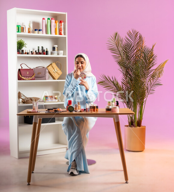 أزياء واكسسوارات نسائية عصريه، إمرأة عربية خليجية عمانية محجبة ترتدي عباءة زرقاء تقوم بوضع أحمر الشفاه، مفهوم الانوثه والاهتمام بالمظهر الخارجي, أدوات تجميل نسائيه عصريه، التسويق لمنتجات التجميل, مكياج وميكاب تتوريال, صالون نسائي راقي