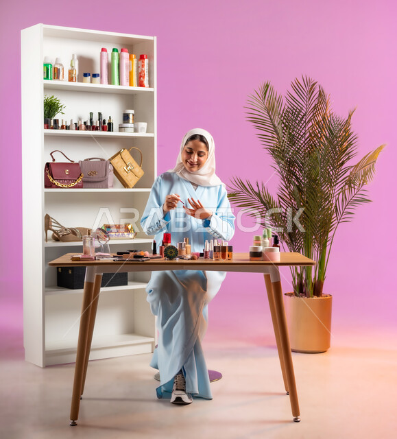 اكسسوارات وأزياء نسائية عصريه، إمرأة عربية خليجية عمانية محجبة ترتدي عباءة زرقاء تقوم بوضع طلاء الأظافر، مفهوم الانوثه والاهتمام بالمظهر الخارجي, أدوات تجميل نسائيه عصريه، التسويق لمنتجات التجميل, مكياج وميكاب تتوريال, صالون نسائي راقي