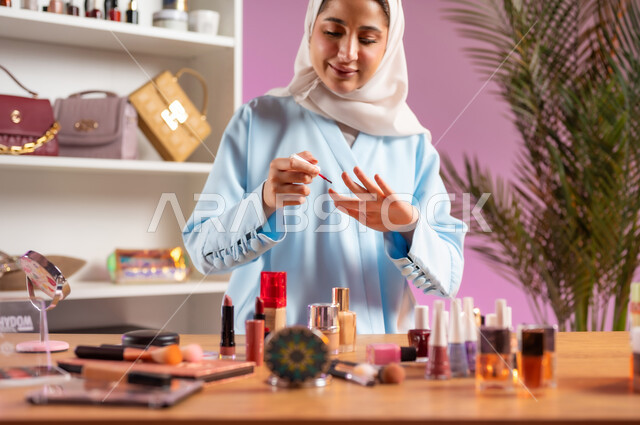 اكسسوارات وأزياء نسائية عصريه، إمرأة عربية خليجية عمانية محجبة ترتدي عباءة زرقاء تقوم بوضع طلاء الأظافر، مفهوم الانوثه والاهتمام بالمظهر الخارجي, أدوات تجميل نسائيه عصريه، التسويق لمنتجات التجميل, مكياج وميكاب تتوريال, صالون نسائي راقي