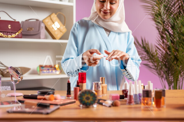اكسسوارات وأزياء نسائية عصريه، إمرأة عربية خليجية عمانية محجبة ترتدي عباءة زرقاء تقوم بوضع طلاء الأظافر، مفهوم الانوثه والاهتمام بالمظهر الخارجي, أدوات تجميل نسائيه عصريه، التسويق لمنتجات التجميل, مكياج وميكاب تتوريال, صالون نسائي راقي