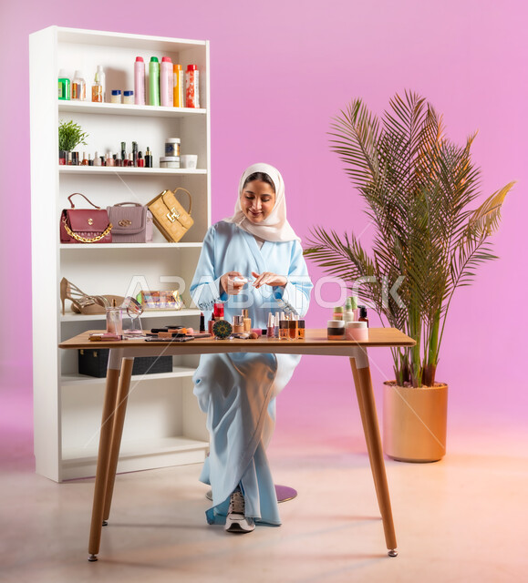 اكسسوارات وأزياء نسائية عصريه، إمرأة عربية خليجية عمانية محجبة ترتدي عباءة زرقاء تقوم بوضع طلاء الأظافر، مفهوم الانوثه والاهتمام بالمظهر الخارجي, أدوات تجميل نسائيه عصريه، التسويق لمنتجات التجميل, مكياج وميكاب تتوريال, صالون نسائي راقي