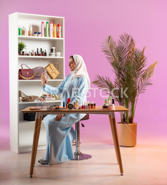 روائح عطور وطنية فخمة، فتاه عربية خليجية عمانية محجبة ترتدي عباءة زرقاء تحمل بيدها زجاجة عطر، مفهوم الانوثه والاهتمام بالمظهر الخارجي, أدوات تجميل نسائيه عصريه، التسويق لمنتجات التجميل, مكياج وميكاب تتوريال, صالون نسائي راقي