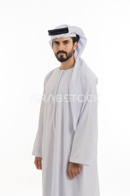 The concept of elegance, masculinity and interest in outward appearance, standing straight and looking at the camera with gestures of self-confidence, a full-length portrait of an Arab Gulf Emirati man wearing a white Emirati kandura and ghutra, standing with gestures of masculinity and self-esteem, white background