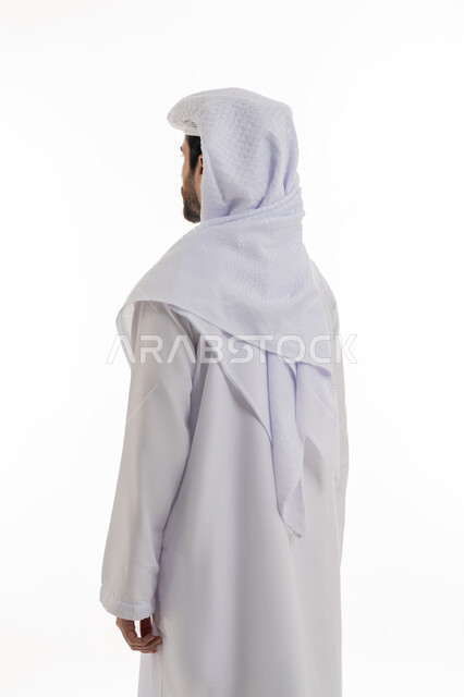 مفهوم الاناقه والرجوله والاهتمام بالمظهر الخارجي، بورتريه بالطول الكامل من الخلف لرجل عربي خليجي اماراتي يرتدي الكندوره والغتره البيضاء الاماراتيه يقف بشكل خلفي بايماءات الرجوله وعزه النفس، خلفيه بيضاء